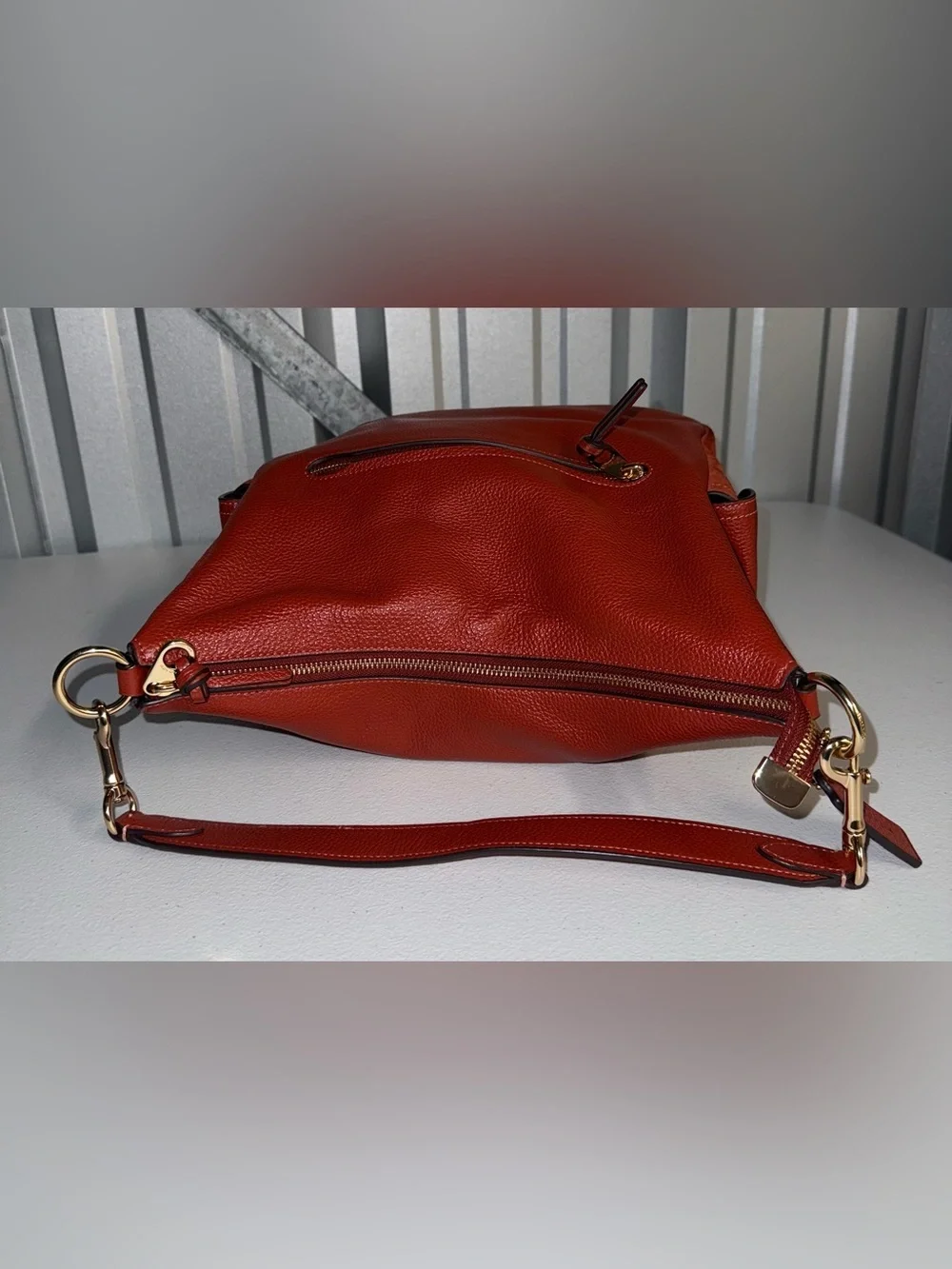 Coach Pennie Shoulder Bag features gold hardware and side suede pockets